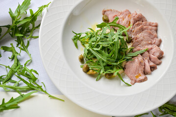 sliced ​​meat on a plate with arugula