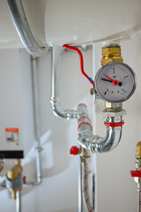 Pressure gauge displaying current bar level on a complex system of water pipes and valves