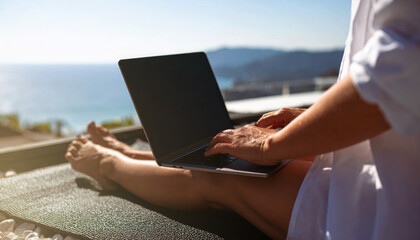 Faceles of a person sitting typing on a laptop while relaxing on a sunny balcony with a beautiful sea view.