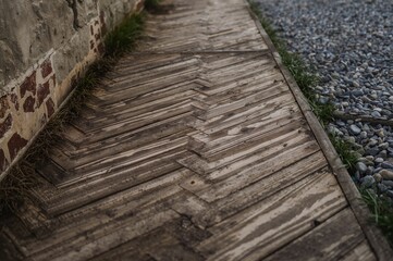 Timber decking pathway bordered by a wall and stones