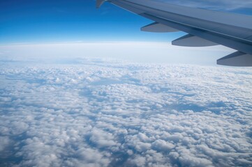 Obraz premium Soaring over a cloud ocean under a limitless sky from a window seat perspective.