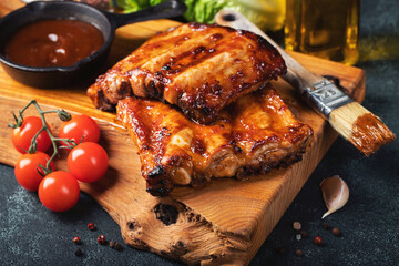 Spicy hot grilled spare ribs from a summer BBQ served with a hot chili pepper and fresh tomatoes