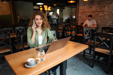Freelancer talking on the phone and working on laptop in a cafe