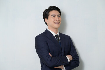 白背景で腕組みをするスーツの日本人男性