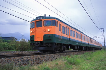 Obraz premium 浅間山に見守られて曇天の軽井沢を走行するしなの鉄道115系電車(湘南色)_2025/10/4撮影