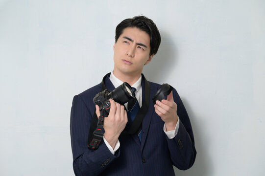 Fototapeta 白背景でカメラを持って悩むスーツの日本人男性