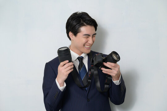 Fototapeta カメラとレンズを持って喜ぶスーツの日本人男性