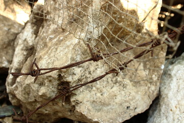 Rusty barbed wire entangled with old metal mesh