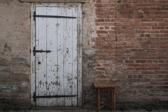 Weathered white wooden door set against a red brick backdrop with a vintage look. - Powered by Adobe