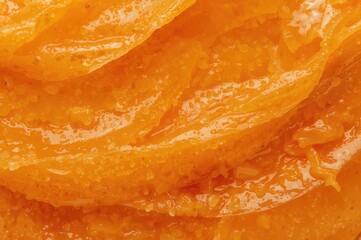 Detailed view of vibrant orange industrial lubricant with dense consistency for reducing metal friction. Thick lubricating grease close-up.