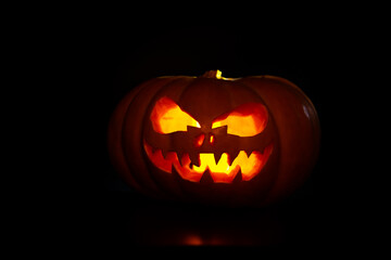 Halloween pumpkin with a scary glowing face on a black background.