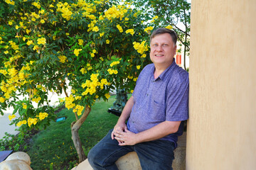 Man in a Summer Shirt Relaxing on His Porch Enjoying Peaceful Moment at Home, Embracing the Warmth of a Sunny Day and Cozy Atmosphere.