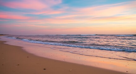 Fototapeta premium A serene beach scene at sunset with gentle waves lapping the shore under a colorful sky.