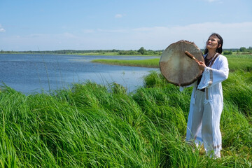 Shaman woman drumming in the natural environment