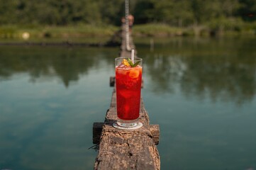Scarlet beverage perched on a suspension bridge spanning the stream