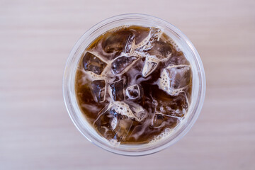 A cup filled with iced americano coffee and ice cubes, top view