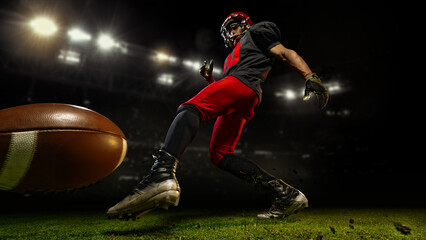 American football player kicking ball mid-motion under bright 3D stadium lights. Concept of action,...