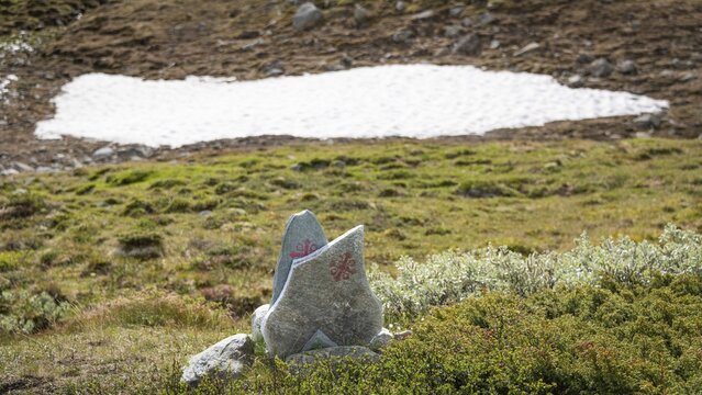 Olavskreuz auf Steinen, Wegmarkierung f&uuml;r Pilger, dahinter kleines Schneefeld in bergiger Landschaft, Pilgerweg Olavsweg, Olavsleden oder Pilgrimsleden, Dovrefjell, Norwegen