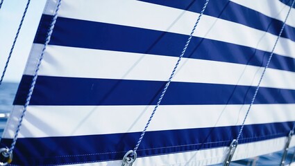 Sailboat sail with blue and white stripes close-up view.