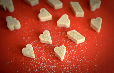 Heart and various shaped brown sugar on red background
