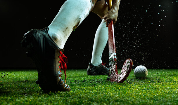 Field hockey player in action during intense match with flying grass particles. Concept of competition and teamwork for editorial design, sports branding, and motivation projects.