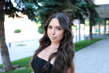 Woman in the street. Portrait of young happy woman on city street looking at camera. Confident stylish girl outdoor with copy space. Proud and satisfied woman standing on street. High quality photo