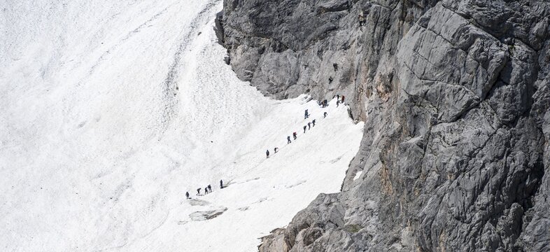 Mountaineers queuing at the transition from the H&ouml;llentalferner to the Zugspitz via ferrata, on a snowfield, overtourism, mountain basin with glacier remnant of the H&ouml;llentalferner, H&ouml;llental, rocky mountain peaks, H&ouml;llental, Bavaria, Germany