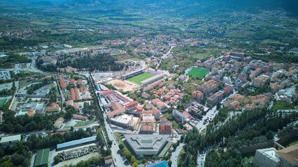 Aerial drone footage of L’Aquila, Italy, showcasing historic architecture, vibrant streets, and the stunning surrounding mountains