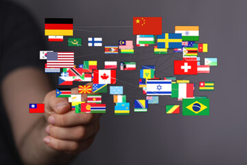 Conceptual image of a hand reaching out, connected with international flags, symbolizing global...