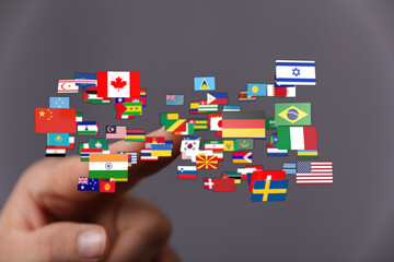 A hand gently touching various flags representing countries, symbolizing global unity and...
