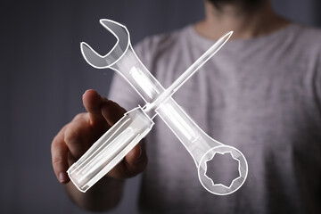 Person interacts with a digital wrench and screwdriver, symbolizing repair, maintenance, or technical support.
