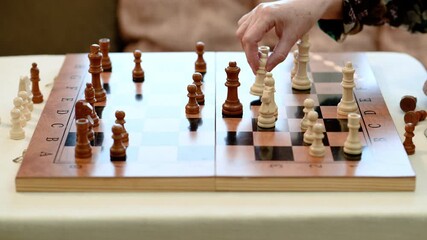 A senior woman moves a white chess piece during a therapeutic session promoting mental health, mindfulness, and emotional focus through cognitive engagement and strategy-based play.