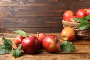 Fresh ripe apples with green leaves on wooden table, closeup