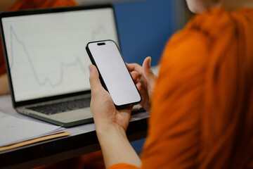 Monks and priests, men in orange robes, use smartphones with white screens.