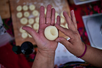 Hands shaping dough into round dumplings for traditional Polish dish during Dozynki festival in Wloclawek, Poland, close-up process, bright daylight.