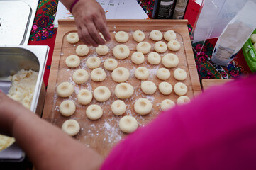 Women arranging homemade dumplings on wooden board during Polish harvest festival in Wloclawek, Poland, top-down view, teamwork cooking.