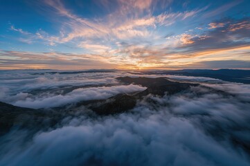 Naklejka premium Aerial view of mountains covered by clouds at dawn