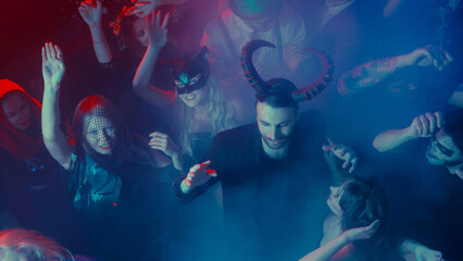 Man with horns costume dancing in smoky Halloween nightclub. Concept of spooky style, nightlife, youth culture, emotional celebration, and festive visuals.