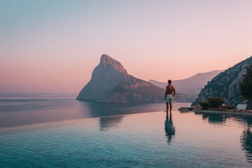 Male tourist from behind relaxing by the pool and enjoying the stunning mountain and sea view