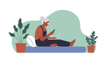 Relaxed senior woman multitasking with laptop and phone at home enjoying technology