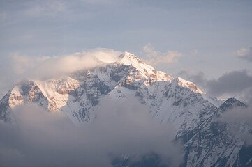 Snow-capped peak beneath a sky filled with white clouds in a vast mountain range