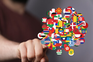 A person's finger touching a network of global flags. This image symbolizes worldwide connection,...