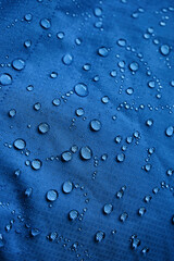 Water drops on waterproof membrane fabric. Detail view of texture of blue waterproof cloth.