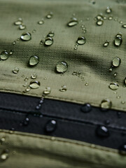 Water drops on waterproof membrane fabric. Detail view of texture of green waterproof cloth.