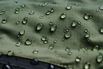 Water drops on waterproof membrane fabric. Detail view of texture of green waterproof cloth.