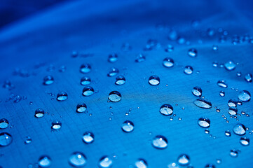 Water drops on waterproof membrane fabric. Detail view of texture of blue waterproof cloth.
