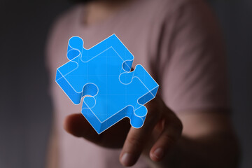 Conceptual image of a hand reaching for a blue puzzle piece representing connection, solution,...