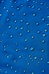 Water drops on waterproof membrane fabric. Detail view of texture of blue waterproof cloth.
