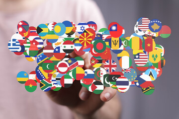 A hand gently touches a collection of flags from various countries, symbolizing global unity, cooperation, and world peace. This conceptual imag