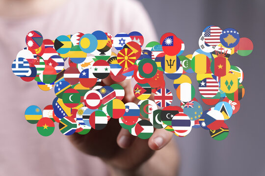 A hand gently touches a collection of flags from various countries, symbolizing global unity, cooperation, and world peace. This conceptual imag